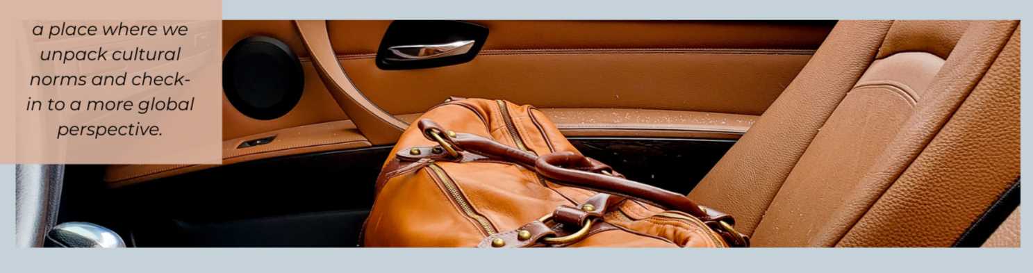 A two-toned brown leather duffle is sitting in a car with brown leather seats. 
